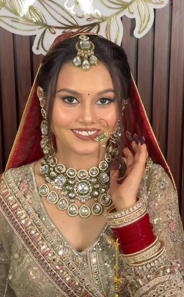 Bride in a gold lehenga with a statement kundan necklace and maang tikka