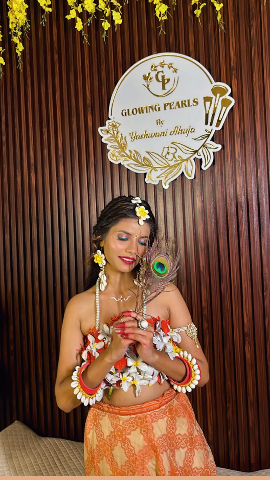 Haldi look with floral jewellery in front of the Glowing Pearls by Yashwani Ahuja sign